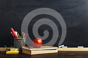 Teacher`s desk with writing materials, a book and an apple, a blank for text or a background for a school theme. Copy space