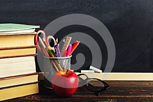 Teacher`s desk with writing materials, a book and an apple, a blank for text or a background for a school theme. Copy space