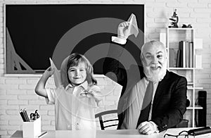 Teacher and school boy with paper airplane. Pedagogue and pupil having fun. Developing caring learners who are actively