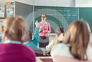 Teacher in school class with pupils sitting and listening