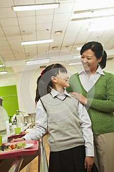 Teacher and school girl portrait in school cafeteria