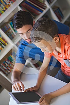 Teacher and school kid using digital table in library