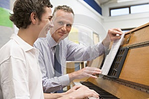 Teacher with schoolboy playing piano