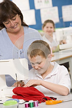 Teacher and schoolboy using a sewing machine