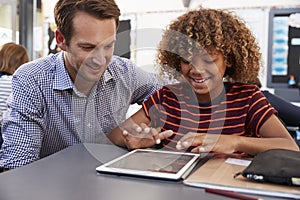 Teacher and schoolboy using tablet computer in class