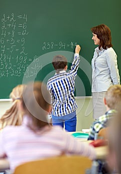 Teacher and schoolboy writing on chalk board