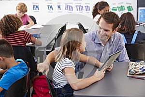 Teacher and schoolgirl with tablet computer looking at each other