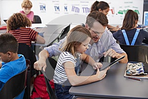 Teacher and schoolgirl using tablet computer in class