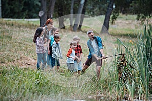 Teacher showing decaying lake plants to school children, during field teaching class. Outdoor active education helping photo