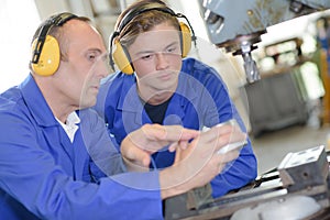 Teacher showing student how to operate machine