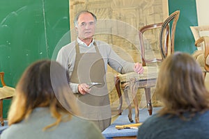 Teacher showing students how to repair chair
