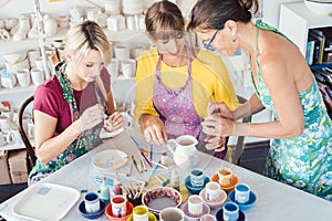 Teacher showing women in workshop how to paint self-made dishes