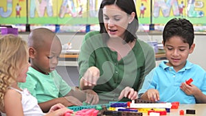 Teacher Sits With Group Of Children Using Construction Kit