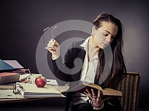 Teacher sitting at her messy desk reading