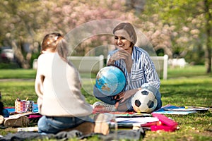 Teacher with small children sitting outdoors in city park, learning group education concept.