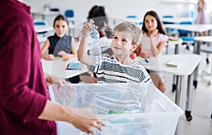 A teacher with small school kids in classroom learning about waste separation.