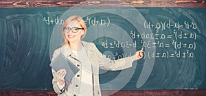 Teacher smart woman with book explain topic near chalkboard. School teacher explain things well and make subject