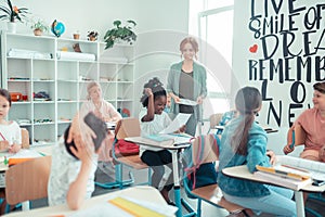 Teacher smiling to her pupils receiving their tests.