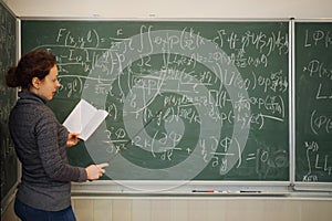 Teacher speaks with book and pointer near