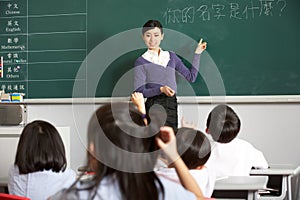 Teacher Standing By Blackboard In Chinese School