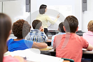 Teacher Standing In Class Using Interactive Whiteboard photo