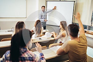 Teacher standing in front of students and showing something on white board in classroom