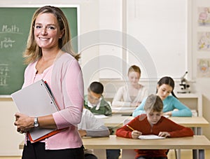 Teacher standing with notebook in classroom photo