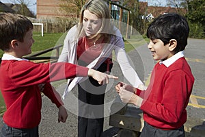 Teacher Stopping Two Boys Fighting In Playground