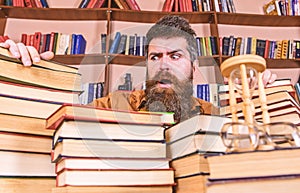 Teacher or student with beard sits at table with books, defocused. Bibliophile concept. Man on confused face between
