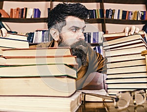 Teacher or student with beard sits at table with glasses, defocused. Bibliophile concept. Man on strict face between