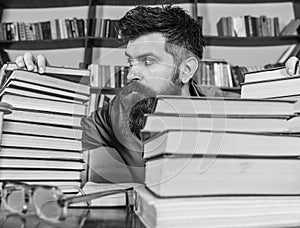Teacher or student with beard sits at table with glasses, defocused. Bibliophile concept. Man on strict face between