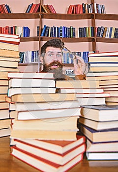 Teacher or student with beard wears eyeglasses, sits at table with books, defocused. Scientific research concept. Man on