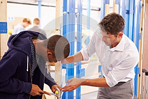 Teacher With Student In Carpentry Class Fitting Door Lock