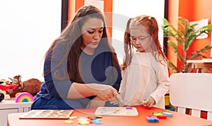 Teacher and student playing with maths puzzle game at kindergarten