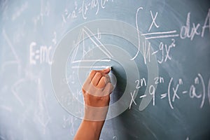 Teacher or student writing on blackboard during math lesson in school classroom