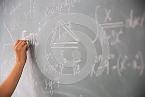 Teacher or student writing on blackboard during math lesson in school classroom