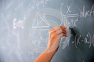 Teacher or student writing on blackboard during math lesson in school classroom