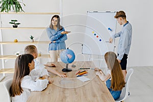 A teacher and students of different ages at a geography lesson. The student answers by standing near the board and tells the story