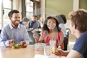 Teacher And Students Eating Lunch In High School Cafeteria During Recess