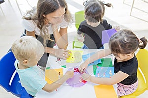 Teacher and students gluing trinkets on a paper