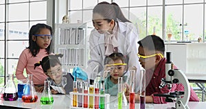 Teacher and students look at experiment on table.