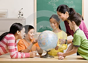 Teacher and students viewing globe in classroom