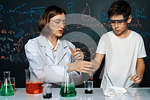 Teacher support schoolboy mixing solution in laboratory STEM class. Erudition.