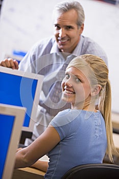 A teacher talks to a schoolgirl using a computer