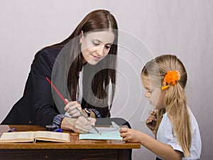 The teacher teaches lessons with a student sitting at the table