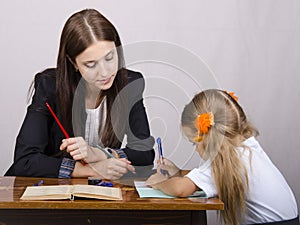 The teacher teaches lessons with a student sitting at the table