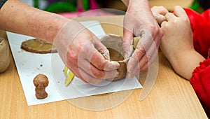 The teacher teaches the student to sculpt with clay.