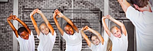 Teacher teaching exercise to school kids in basketball court