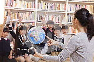 Teacher teaching geography to schoolchildren with a globe