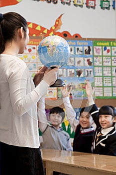 Teacher teaching geography to schoolchildren with a globe